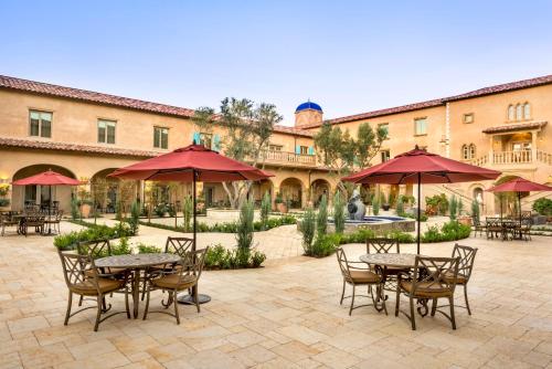 a patio area with tables, chairs and umbrellas at Allegretto Vineyard Resort Paso Robles in Paso Robles