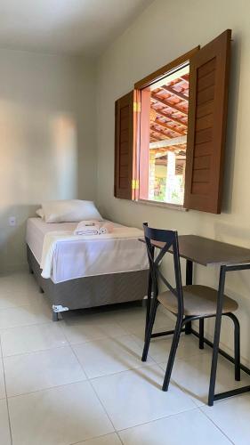 a bedroom with a bed and a desk and a window at Pousada Sitio Parque dos Lençóis in Barreirinhas