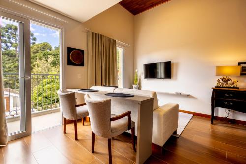 a living room with a table and chairs and a television at Zur Suítes in Campos do Jordão