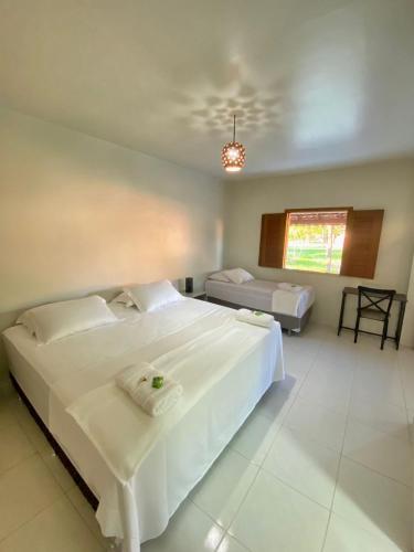 a bedroom with a large white bed and a window at Pousada Sitio Parque dos Lençóis in Barreirinhas