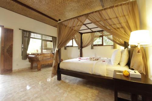 a bedroom with a large bed with a canopy at Pekak Mangku Guest House in Ubud