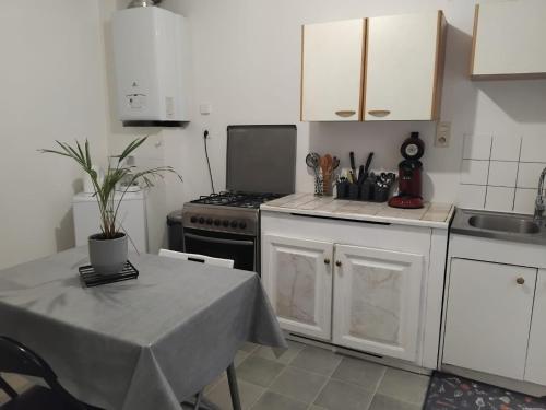 une cuisine avec des armoires blanches, une table et une cuisinière dans l'établissement Appartement F3 centre de Mirecourt, à Mirecourt