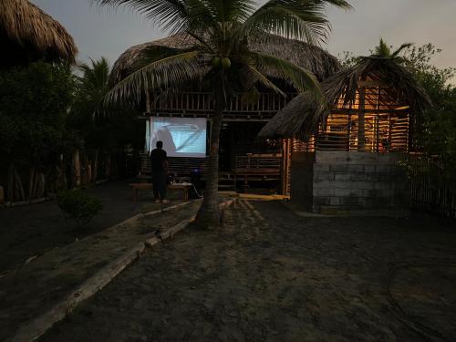 a person standing under a palm tree in front of a screen at Cabaña Kindi in Moñitos