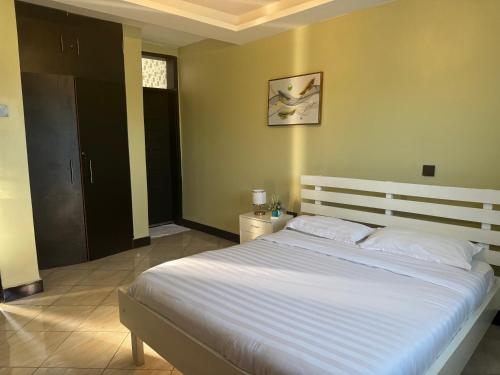 a bedroom with a large bed with white sheets at Fivas Residences in Arua