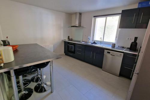 a kitchen with black cabinets and a sink and a dishwasher at Maison vue exceptionnelle in Niaux