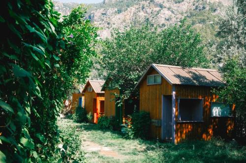 two wooden cottages with trees and mountains in the background at Kaplumbağa Bungalows in Fethiye