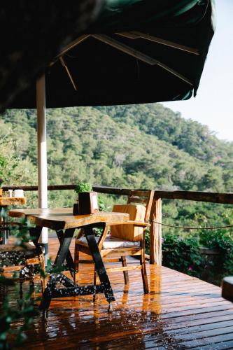 a wooden table and chair on a deck with an umbrella at Kaplumbağa Bungalows in Fethiye