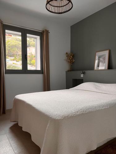 une chambre avec un lit blanc et une fenêtre dans l'établissement T2 Les pieds dans l'eau, à Belvédère