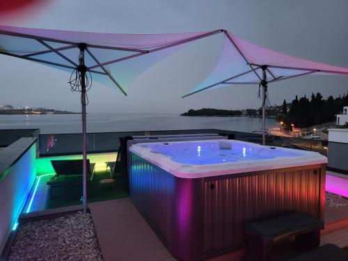 a hot tub on a roof with an umbrella at Cassiopeia - Seaside Retreat in Omišalj