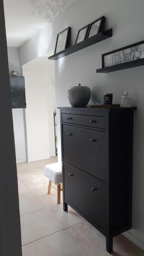 - une commode noire avec un bol au dessus dans l'établissement Maison Normande coeur de ville, à Pont-Audemer