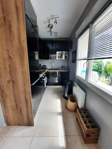 une cuisine avec des armoires noires et une grande fenêtre dans l'établissement Maison Normande coeur de ville, à Pont-Audemer