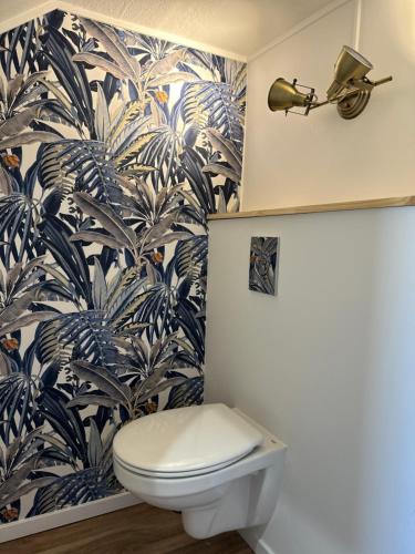 a bathroom with a toilet and a tropical wallpaper at Maison entre Terre et Mer in Blainville-sur-Orne