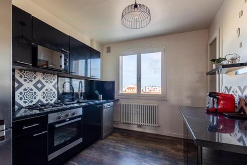 une cuisine avec des armoires noires et une grande fenêtre dans l'établissement Joli appartement cosy, à Valence