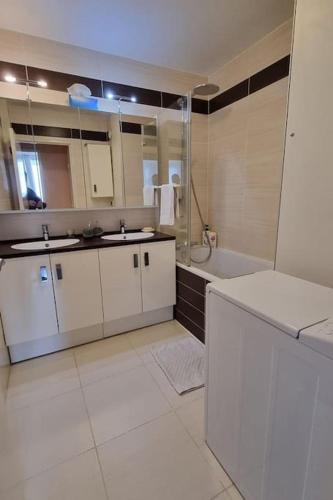 La salle de bains blanche est pourvue d'un lavabo et d'une baignoire. dans l'établissement Appartement avec belle vue sur Paris, à Colombes