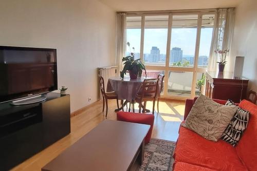 un salon avec un canapé rouge et une table dans l'établissement Appartement avec belle vue sur Paris, à Colombes