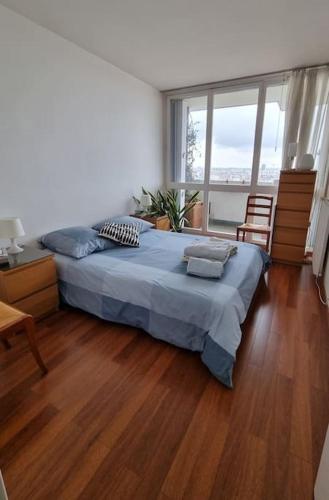 une chambre avec un grand lit et un parquet dans l'établissement Appartement avec belle vue sur Paris, à Colombes