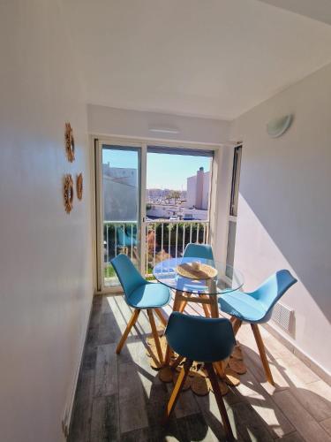 une salle à manger avec une table en verre et des chaises bleues dans l'établissement Appartement Centre-Port Cap d Agde, au Cap d'Agde
