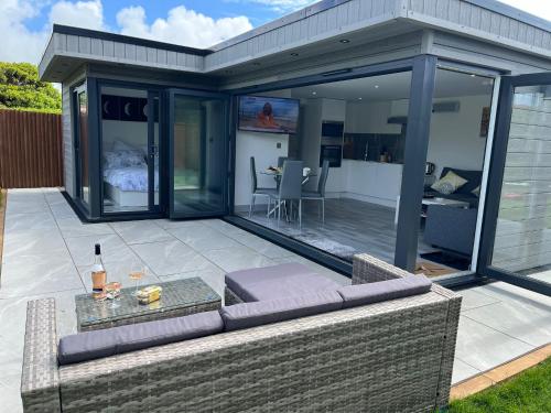 an open patio with a couch and a table at Whispering Waves Guest house, Brighton-8 mins, Guests 4, Beachfront, Free parking, WiFi, Kitchen and AC in Peacehaven