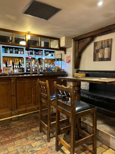 a bar in a pub with two chairs and a counter at The Ram at Tivetshall in Tivetshall Saint Margaret
