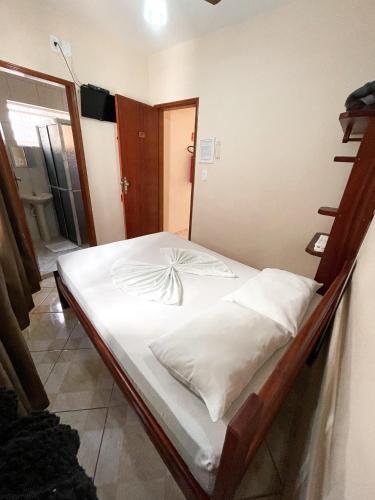 a bedroom with a bed with white sheets at Pousada Santa Rosa in Aparecida