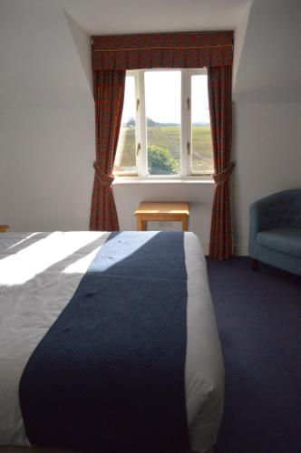 a bedroom with a bed and a window with a chair at The Ram at Tivetshall in Tivetshall Saint Margaret