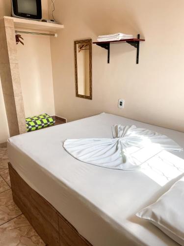 a white bed in a room with a tv at Pousada Santa Rosa in Aparecida