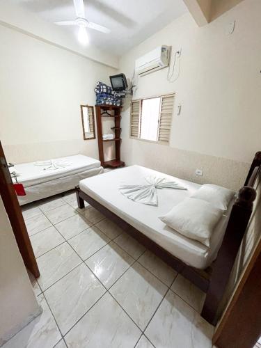 two beds in a room with a tv at Pousada Santa Rosa in Aparecida