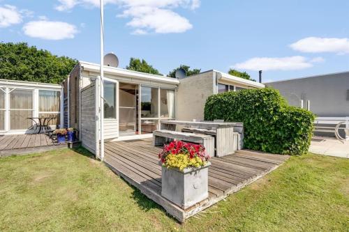 a house with a wooden deck with flowers on it at NIEUW Bootique Frysk huske Langweerderwielen in Boornzwaag