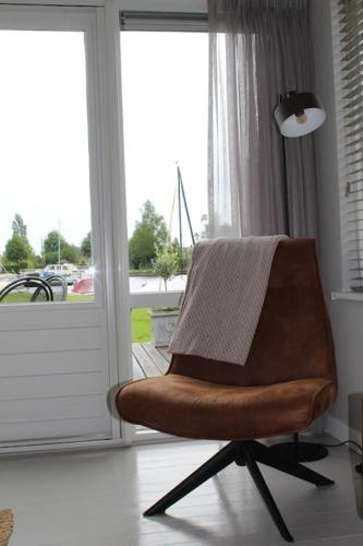 a brown chair sitting in front of a window at NIEUW Bootique Frysk huske Langweerderwielen in Boornzwaag