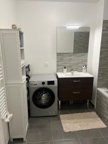 une salle de bain avec une machine à laver et un lavabo dans l'établissement Fati appart, à Sannois