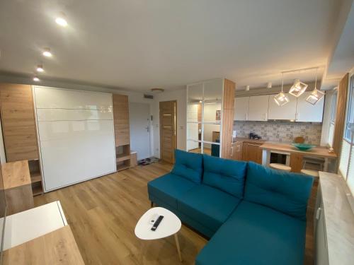 a living room with a blue couch and a kitchen at DiM Suwałki Pułaskiego in Suwałki