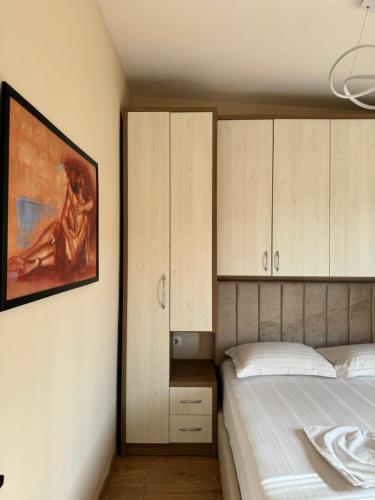 a bedroom with a bed and a painting on the wall at Haris Apartments Tirana in Tirana