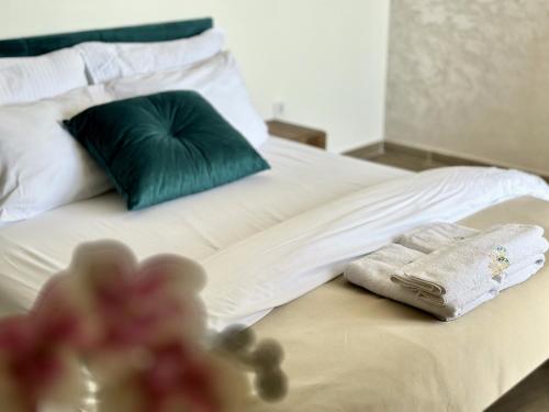 a bed with a green pillow and towels on it at Akhdar Apartments in Utjeha