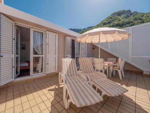 a patio with two chairs and an umbrella on a balcony at Apartments Marina in Sveti Stefan