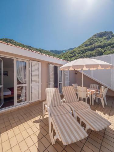 a patio with two chairs and an umbrella and a table at Apartments Marina in Sveti Stefan