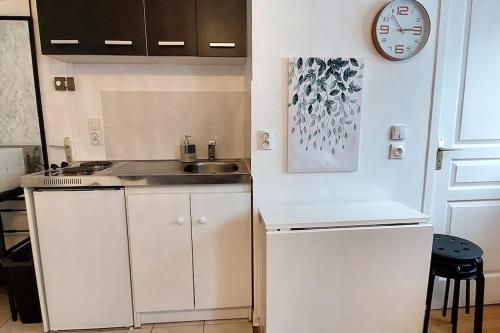 une petite cuisine avec un évier et une horloge murale dans l'établissement Disneyland 4 personnes Wifi Box Proche Gare Bus, à Esbly