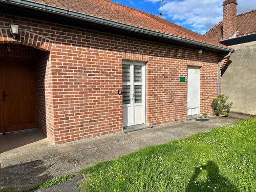 a brick house with a white door and a garage at Appartement Cosy in Sainghin-en-Mélantois