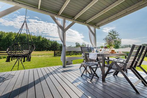 a porch with a swing and a table and chairs at Pod Żurawiem Urokliwy domek na Kaszubach in Michalin