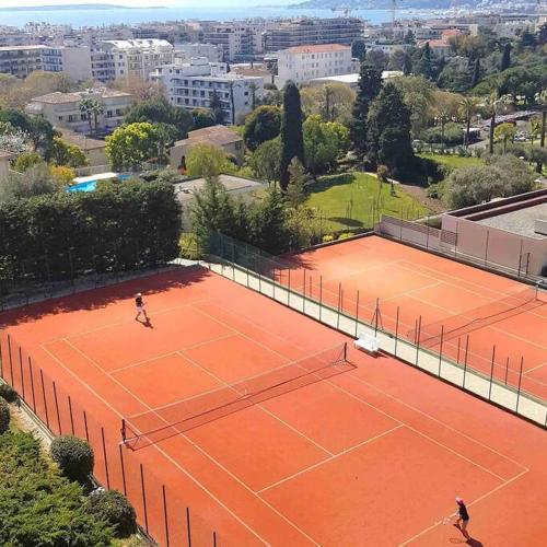 2 personnes jouant au tennis sur un court dans l'établissement Luxueux Appartement 3 pièces, à Antibes