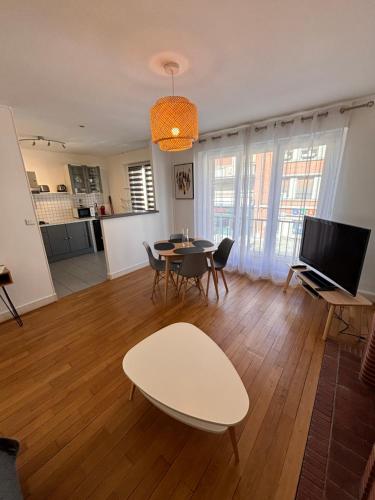 a living room with a table and chairs and a television at Honoriane - Appartements meublés in Gien