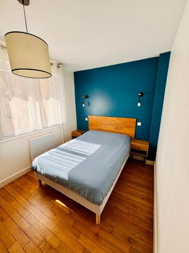 a bedroom with a bed with a blue wall at Honoriane - Appartements meublés in Gien
