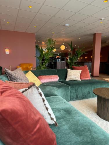a living room with green couches with colorful pillows at Hotell Sillen in Lysekil