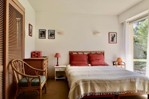 une chambre avec un lit avec des oreillers rouges et une fenêtre dans l'établissement Villa dans un cadre de verdure 110 m2 proche Golf et Lac, à Soorts-Hossegor