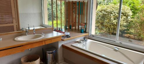une salle de bain avec une baignoire, un lavabo et une fenêtre dans l'établissement Villa dans un cadre de verdure 110 m2 proche Golf et Lac, à Soorts-Hossegor