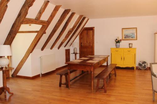 une salle à manger avec une table en bois et du parquet dans l'établissement Gîte de La Devèze - salle de cinéma privée - accueil chevaux, à Goudou