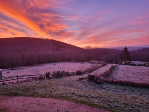 a sunset in a field with a snow covered field at Cascade - Gîte pour 2 personnes in La Salvetat
