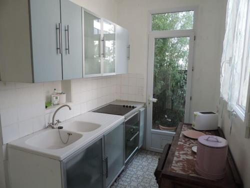 une cuisine blanche avec un évier et une cuisinière dans l'établissement Maison campagne à Paris , wifi, à Fontenay-sous-Bois