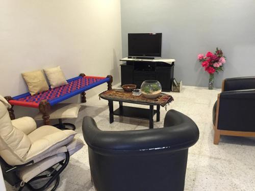 a living room with chairs and a table and a tv at D Zorro HomeTel in Ipoh