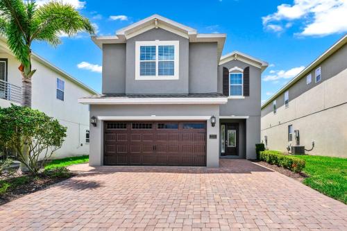 a house with a garage and a palm tree at Charming Home Near Disney With Game Room And Waterpark & Resort Access At Encore Resorts Reunion - 7592Mr in Kissimmee