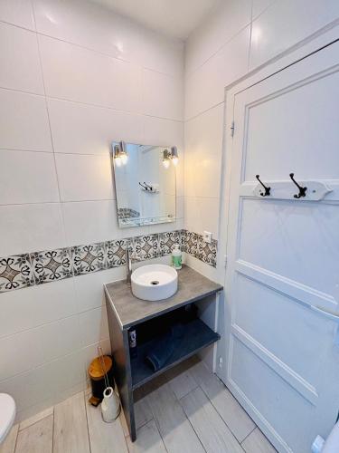 a white bathroom with a sink and a mirror at Le Jeanne d'Arc - Appartements meublés in Gien